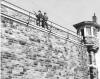 Personnel keep watch on the southeast wall during a prison riot in October 1954